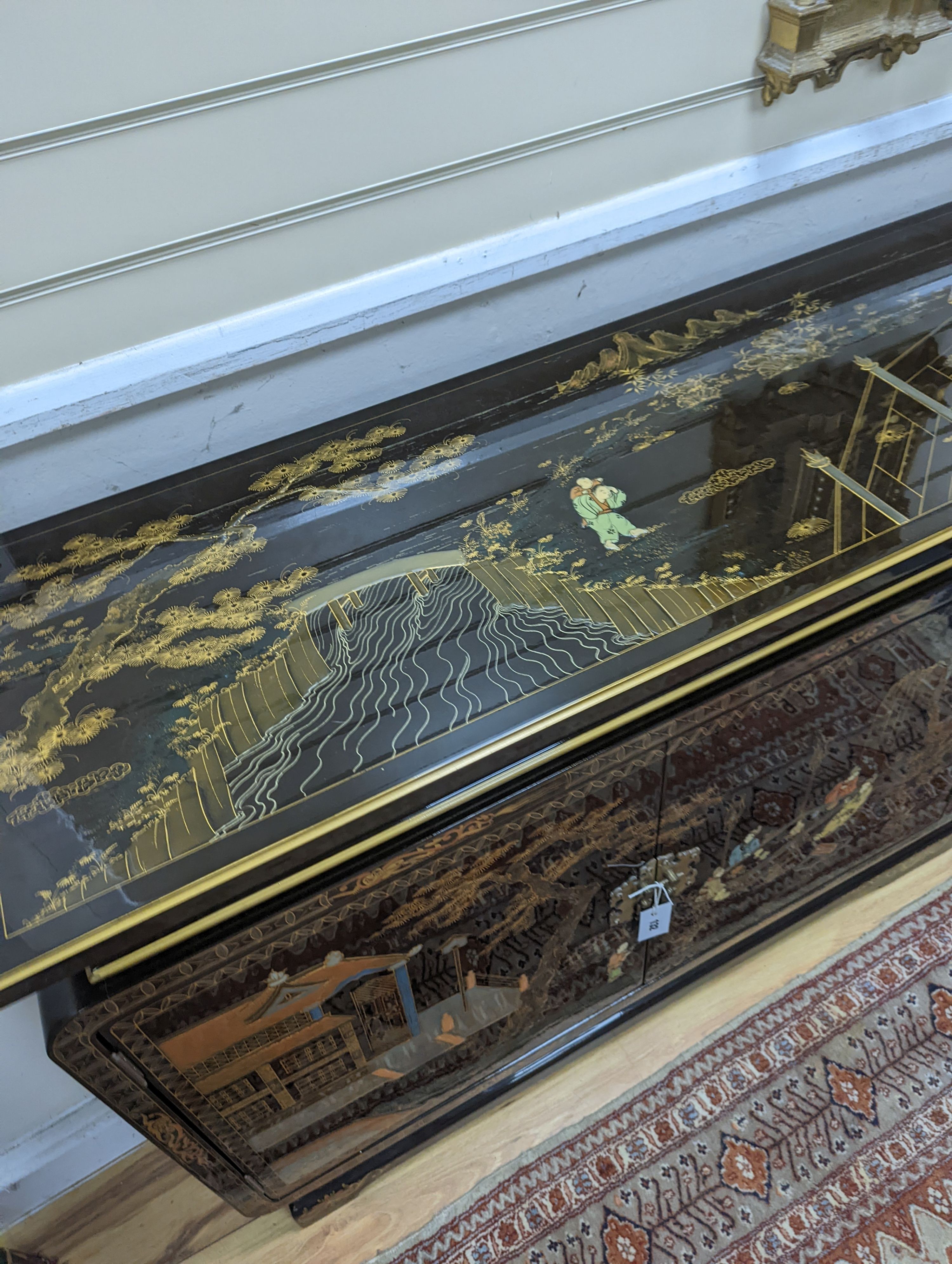 A Chinese lacquer decorated low cabinet. W-200cm, D-45cm, H-75cm.